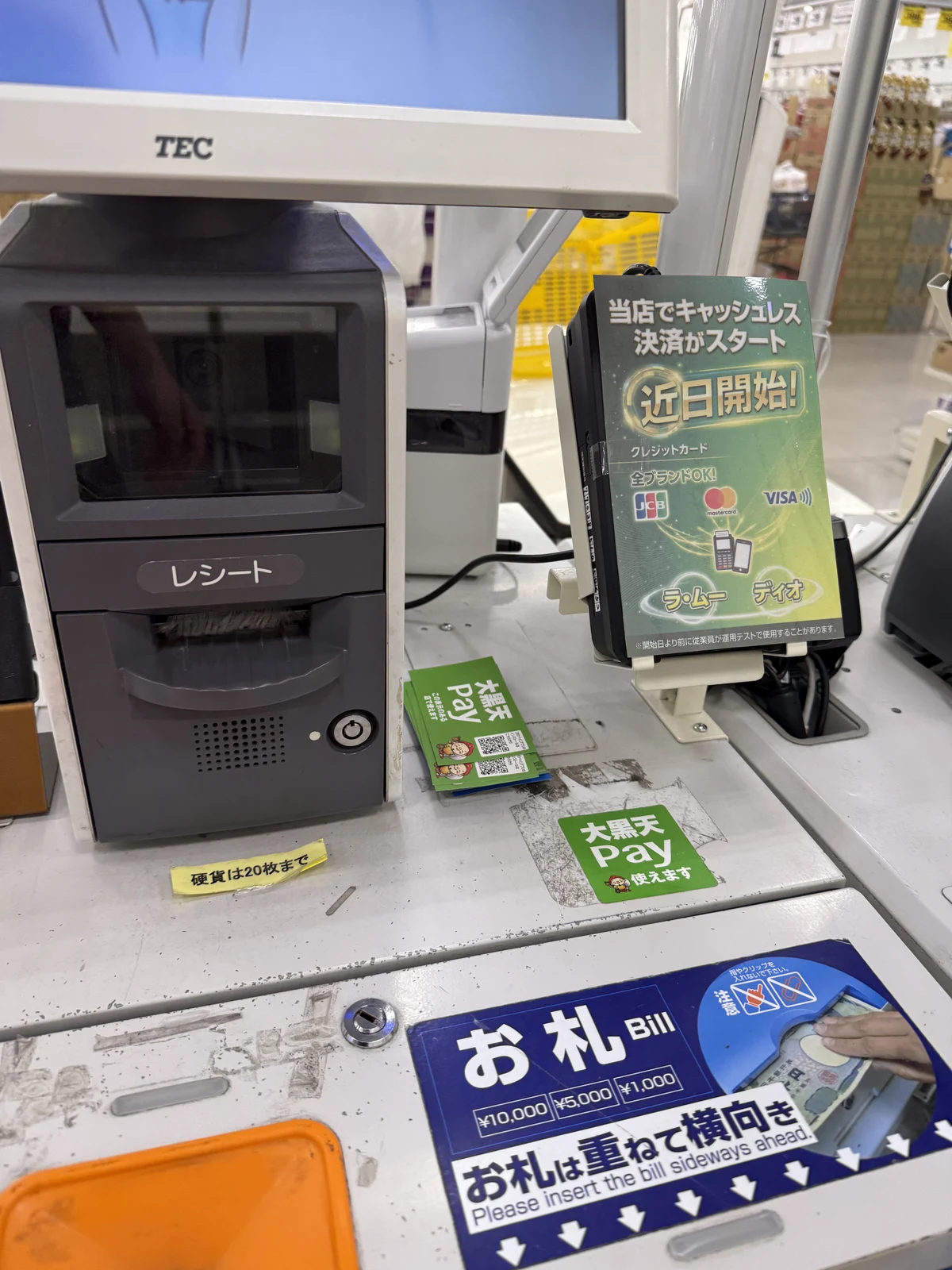 ラ・ムーのセルフレジ横のカード決済端末に「当店でキャッシュレス決済がスタート　近日開始！」の札。JCB・Mastercard・VISAのロゴ